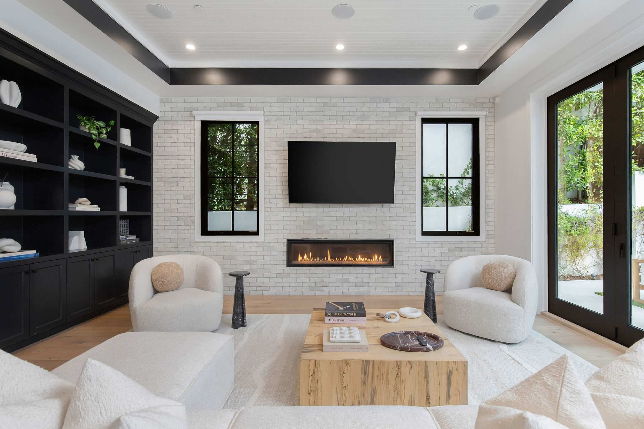A refined lounge anchored by a modern fireplace and tailored shelving in an open-concept layout