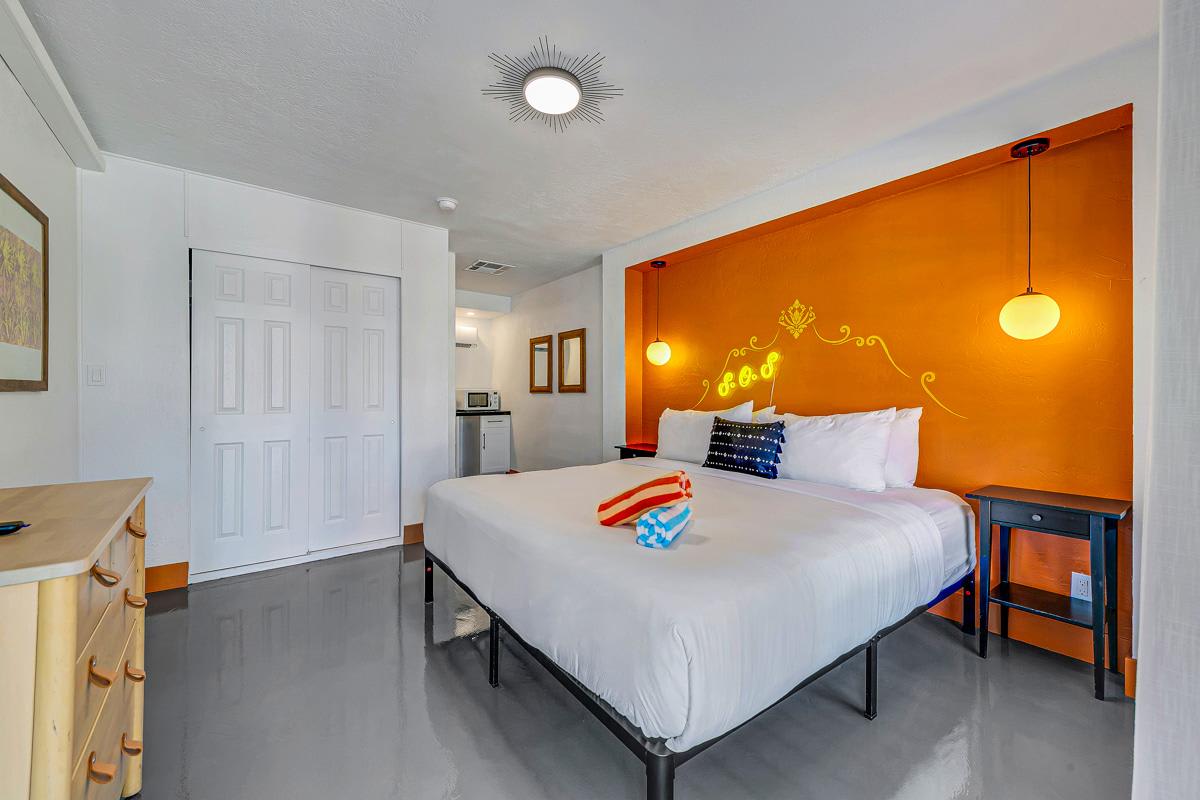 Bedroom with an orange accent wall, white wardrobe and wall-mounted bedside lights.