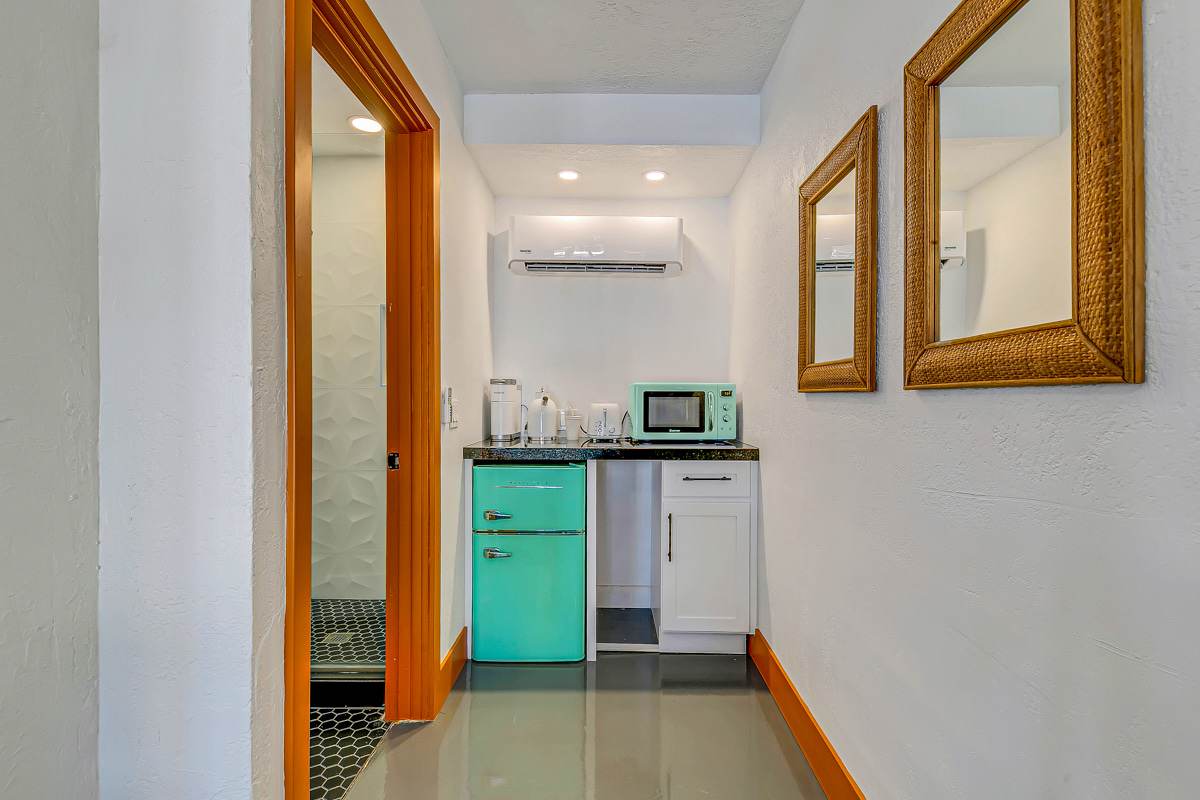 Hallway leading to a compact kitchenette with mint-green cabinetry.