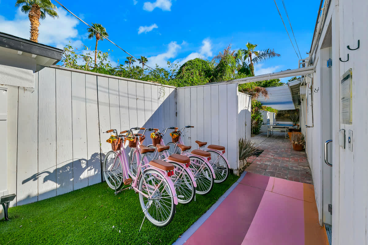 Bicycles lined up along a white fence beside a narrow garden path.