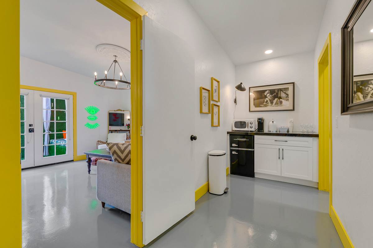 Kitchen and adjoining seating area with yellow trim and a white refrigerator.