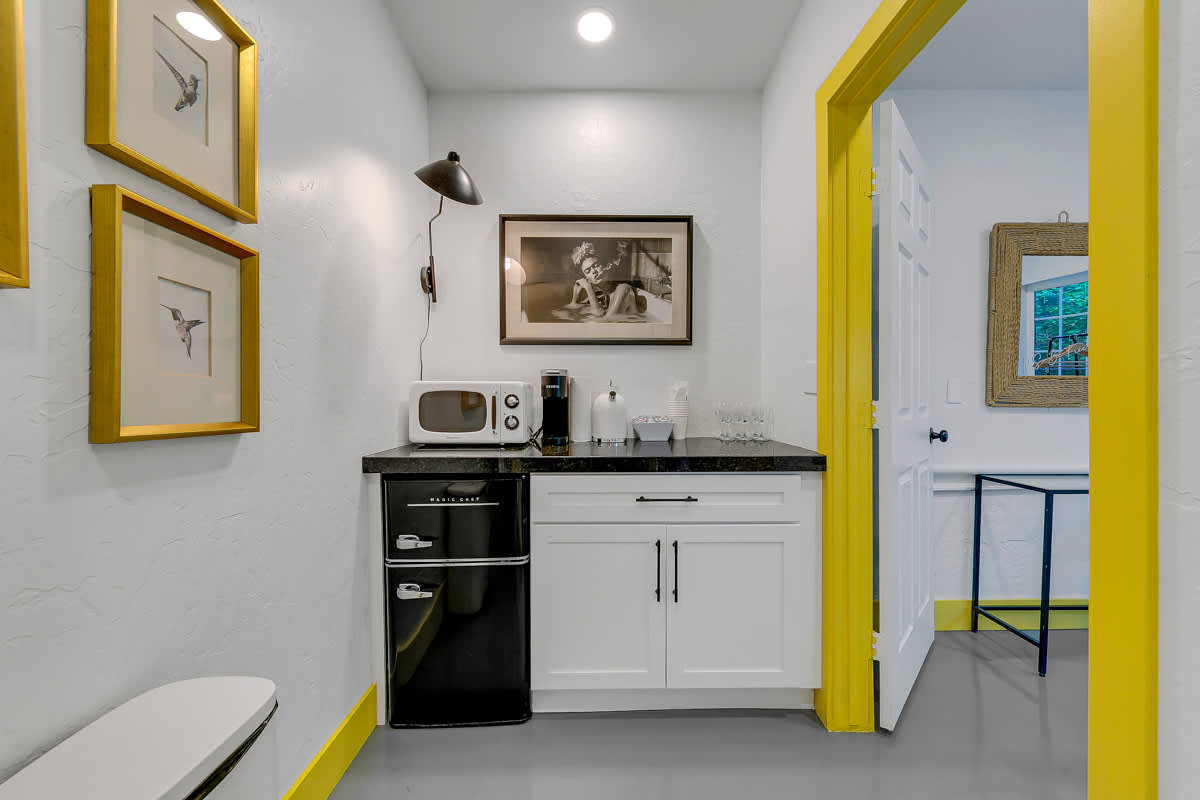 Compact kitchen with a stove, white cabinets and yellow-trimmed doorways.