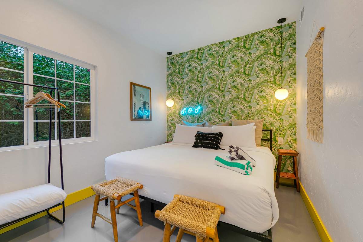 Bedroom with a green leaf-patterned wall, upholstered headboard and mint-green trim.