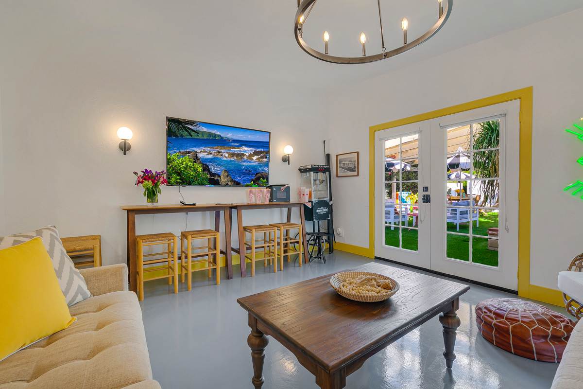 Living and dining area with yellow seating, a coffee table and kitchen beyond.