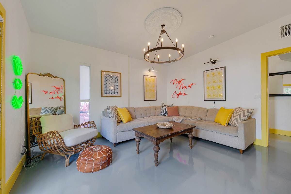 Yellow-accent seating area with framed art, side tables and a green cactus-shaped light.