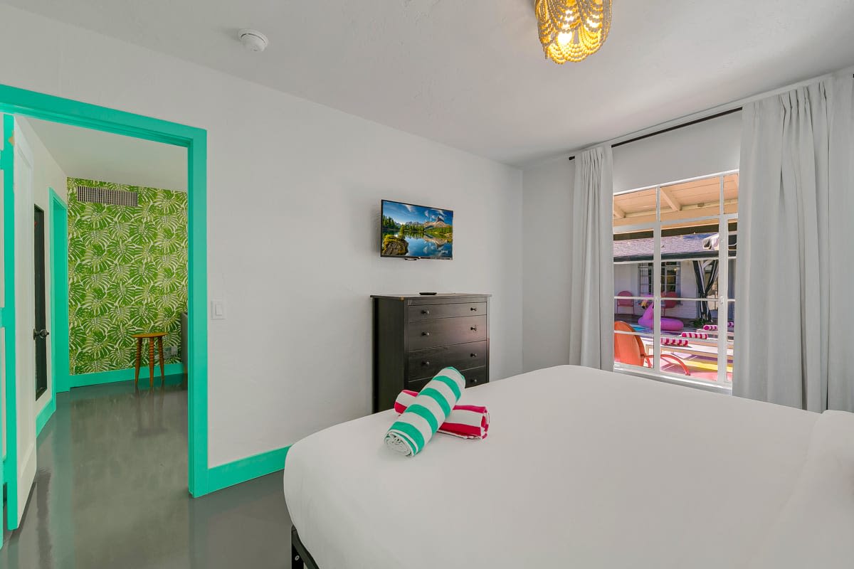 Bedroom with mint-green trim, a wall-mounted television and a white wardrobe.