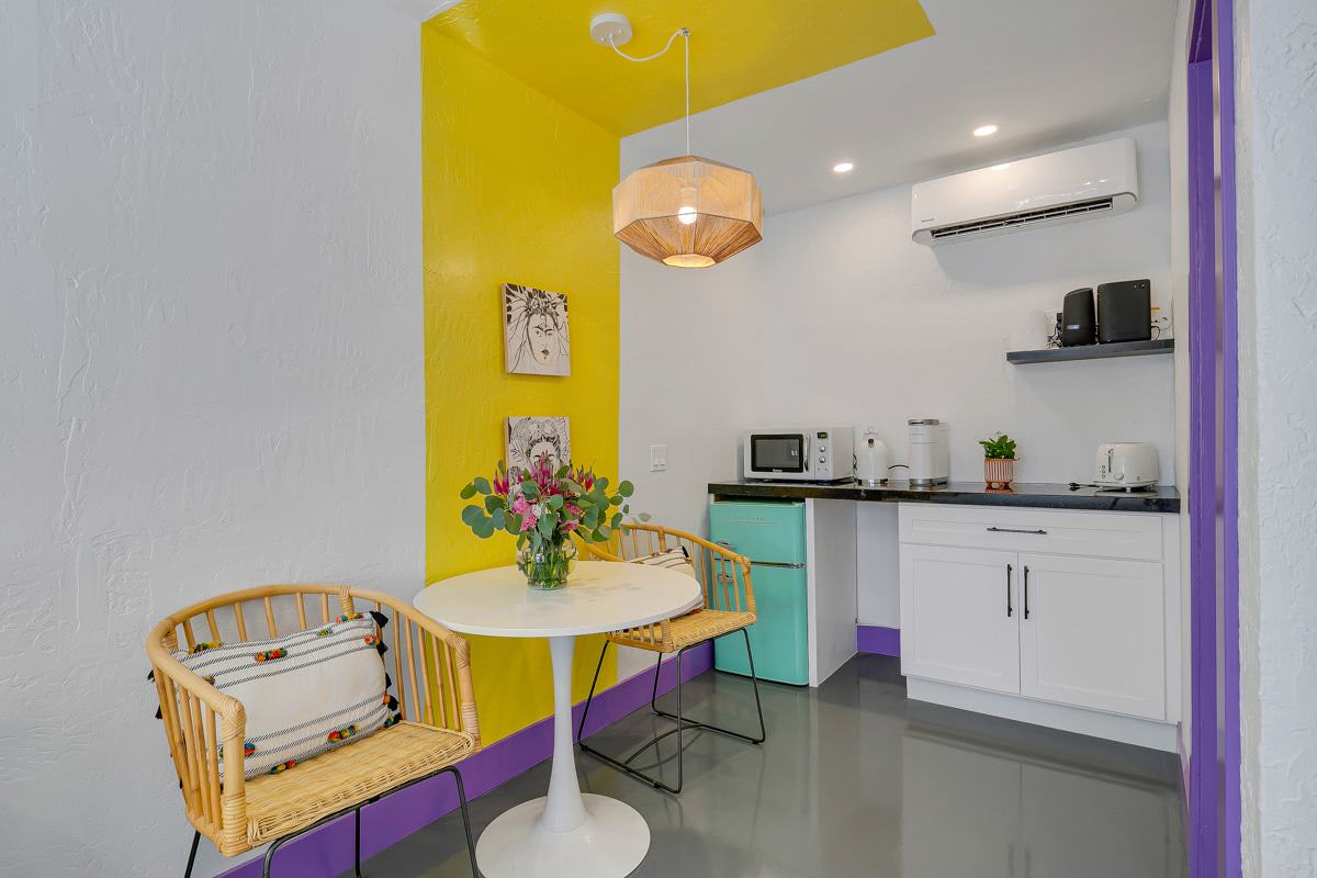 Yellow-accent kitchen and dining nook with white cabinetry and a small round table.