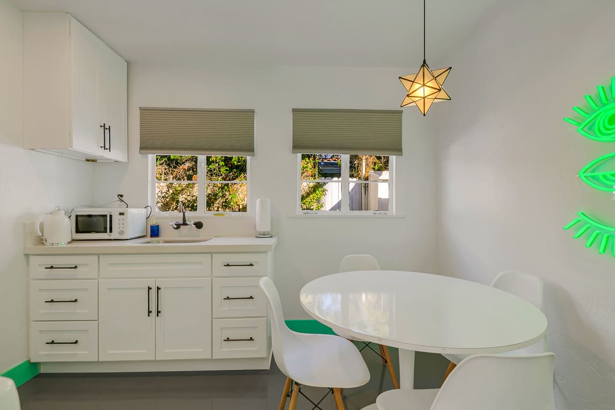 White kitchen cabinetry beside a retro-style refrigerator and round dining table.