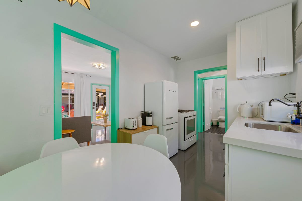 Kitchen view with white counters, cabinets, a round table and mint-green door trim.