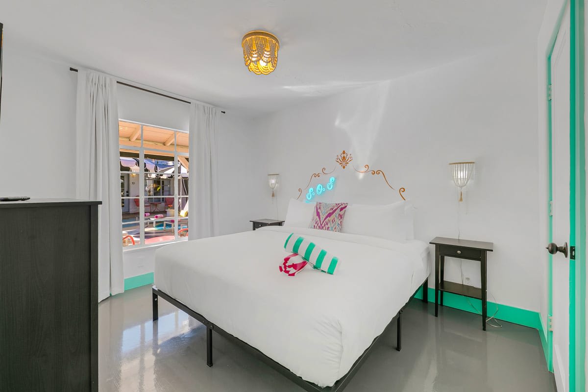 Bedroom with white bedding, a wall-mounted television and mint-green doorway.