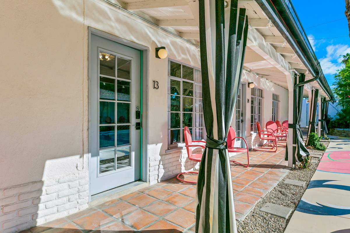 Courtyard walkway with white lounge chairs, French doors and striped awnings.