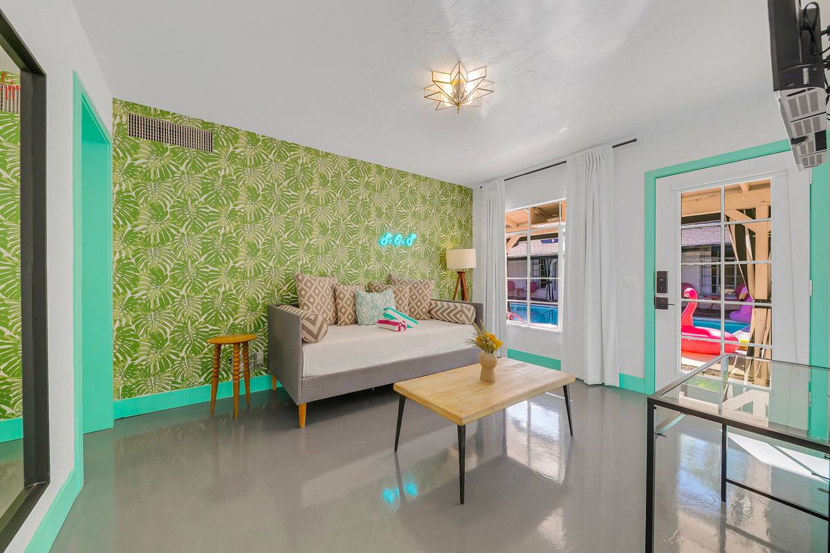 Wide room view with leaf-patterned wallpaper, mint-green trim and glass doors.
