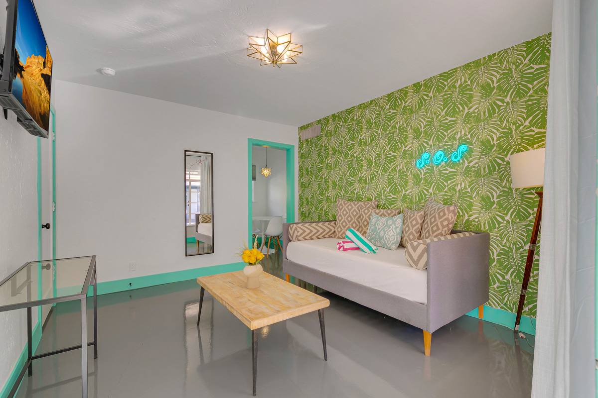 Gray upholstered sleeping area against a green leaf-patterned accent wall.