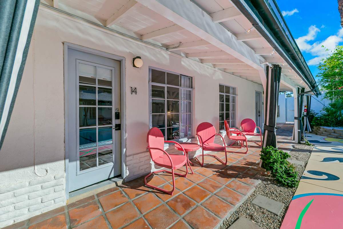 Poolside French doors and pink chairs beneath the exterior awning.