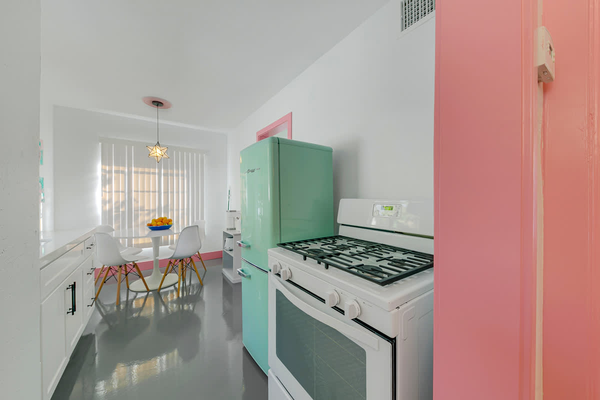 Pink-trimmed kitchen with a mint-green refrigerator, stove and white cabinets.