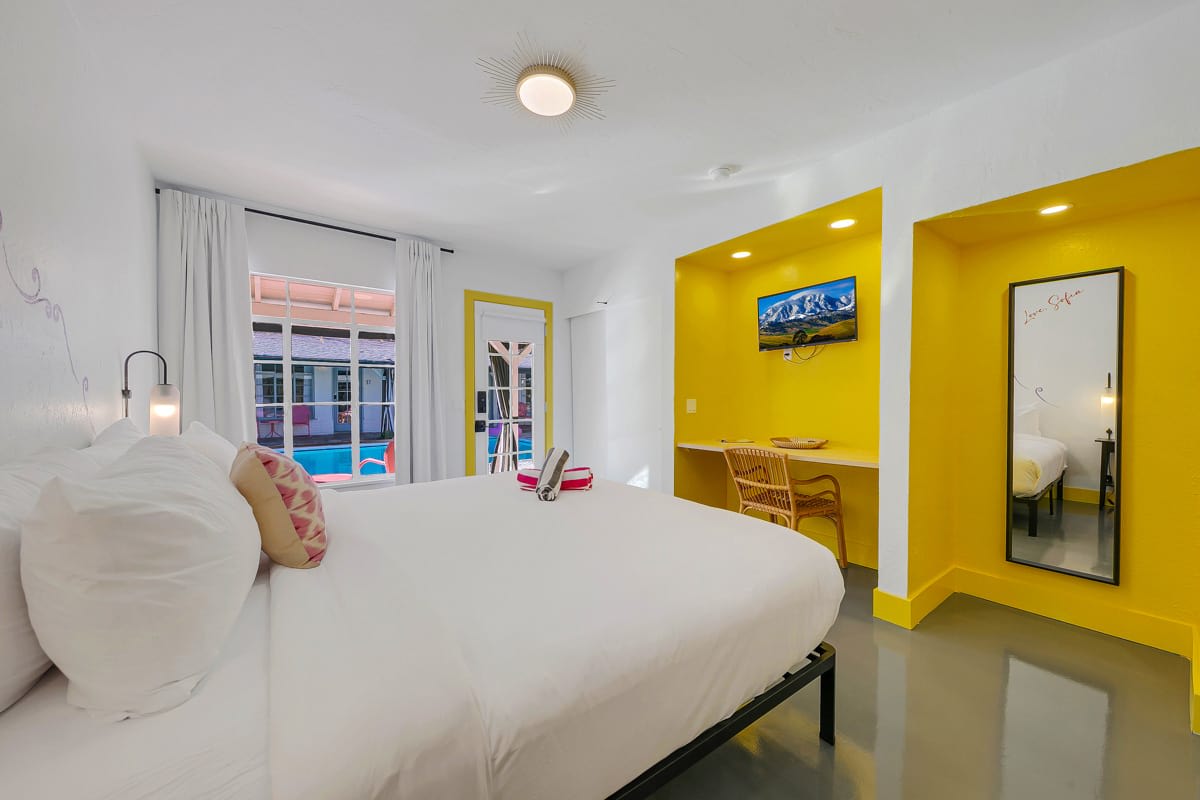 Yellow-accent bedroom with a wall-mounted television and wooden dresser.