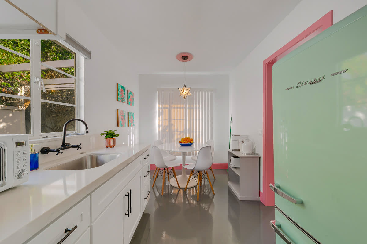Kitchen and round dining table with white cabinetry and pink trim.