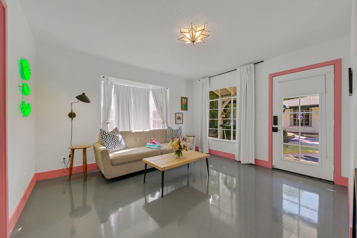 Seating area with a pale sofa, coffee table and pink-trimmed doorways.