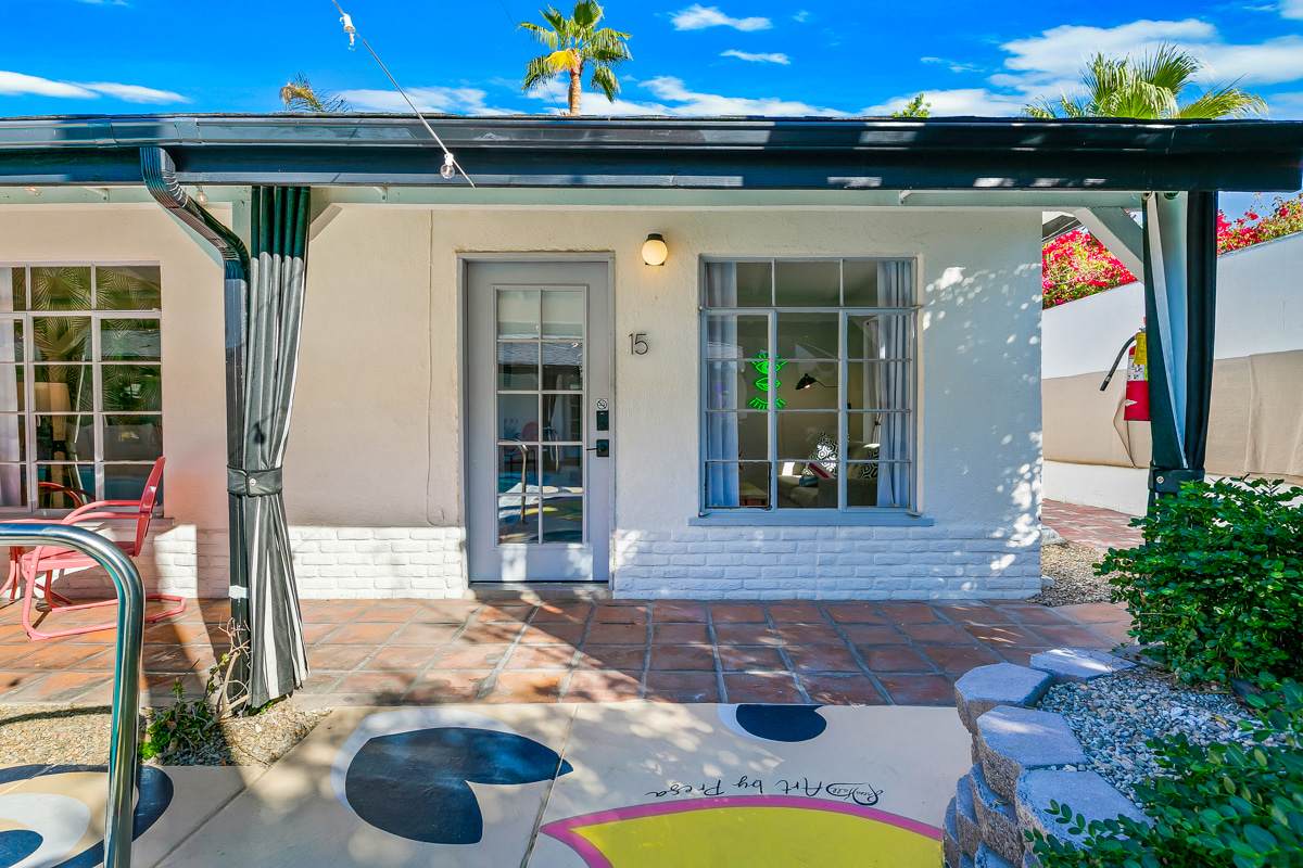 Courtyard entrance with French doors, an awning and decorative painted paving.