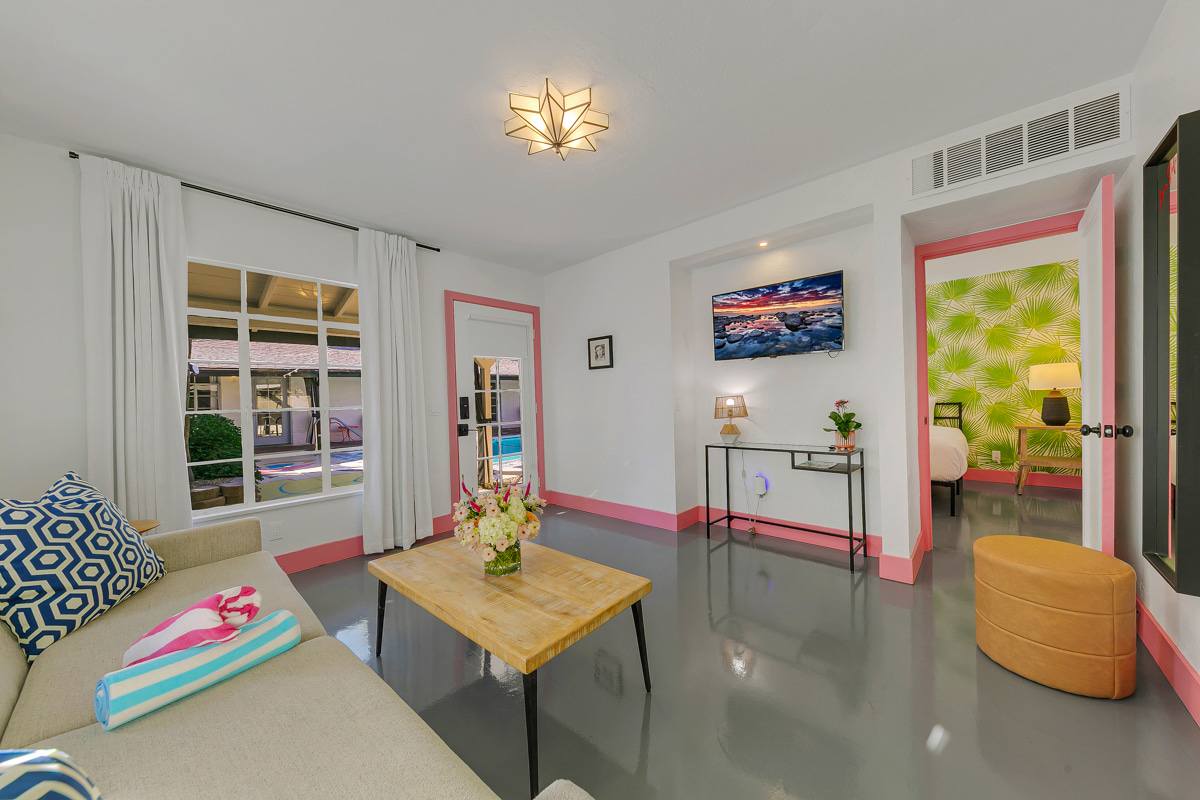Room seating and coffee table beside glass doors and a patterned accent wall.