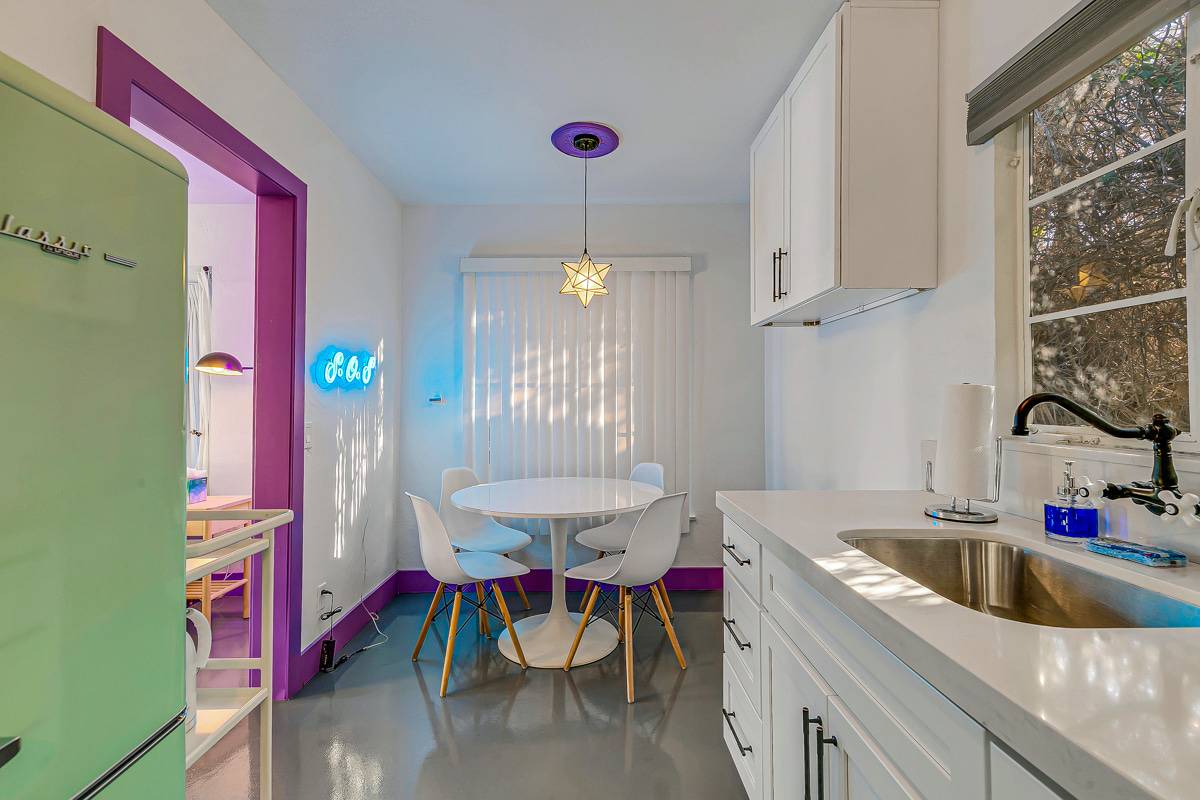 Kitchen counter and dining area with white cabinets and purple accents.