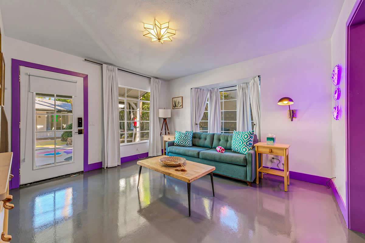 Sitting area with a teal sofa, coffee table and purple-framed glass doors.