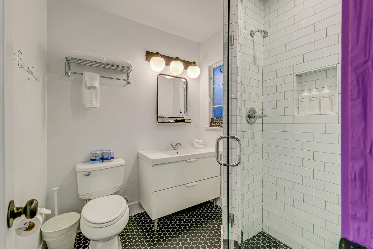 Bathroom with a vanity, walk-in shower and purple-trimmed doorway.
