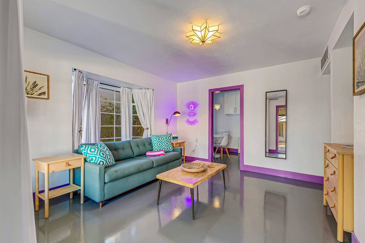 Teal-sofa sitting room with side tables, framed art and purple door trim.