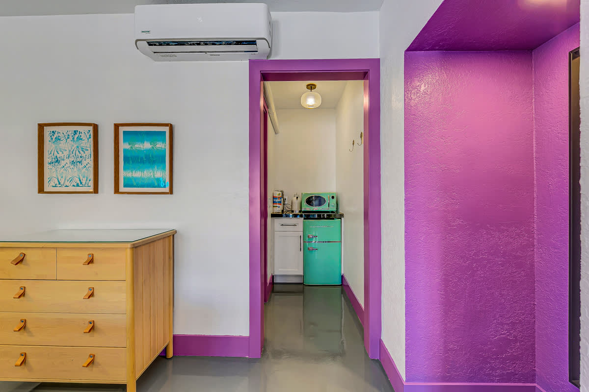 Wood dresser beside a purple-trimmed hall leading toward a kitchenette.