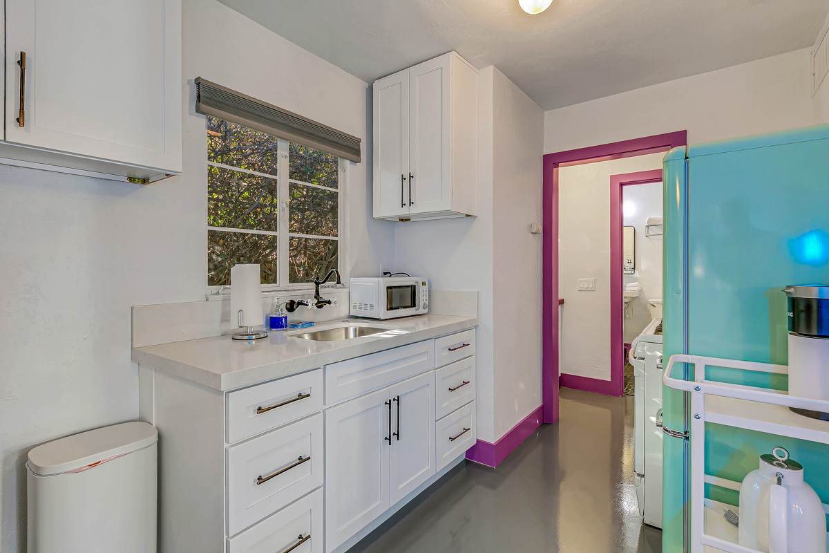White kitchen cabinets and countertop with purple trim and turquoise dining furniture.