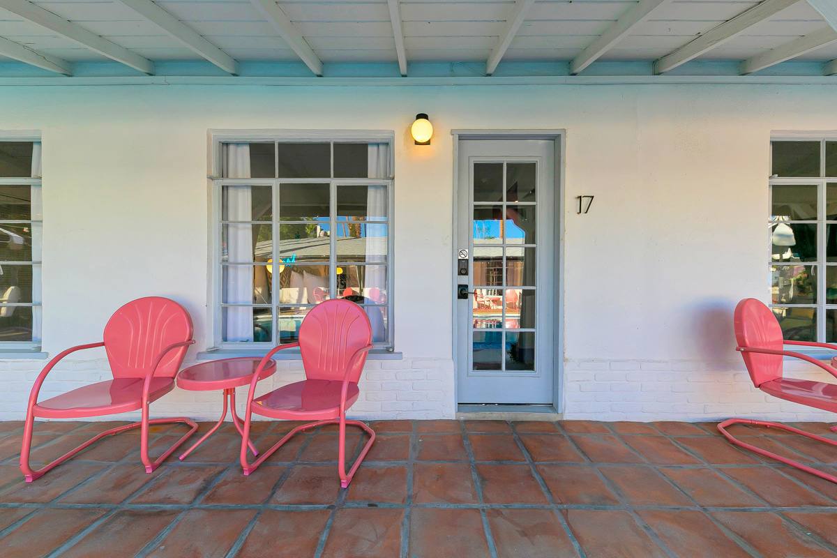 Exterior of room 17 with white French doors and pink outdoor chairs.
