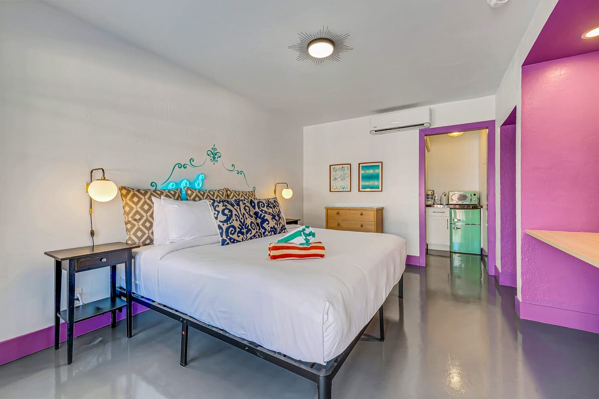 Bedroom with purple shelving, white bedding and a glass courtyard door.
