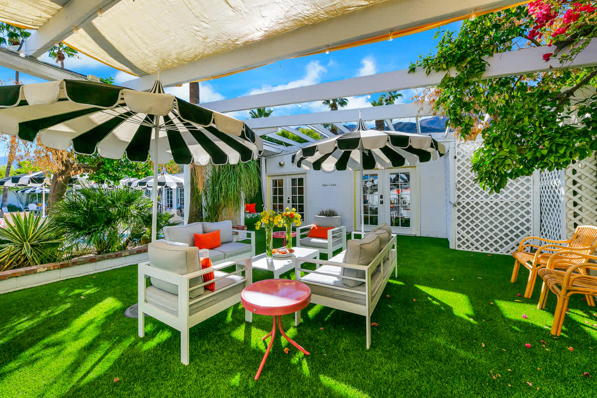 Outdoor tables and chairs beneath green-and-white striped umbrellas.