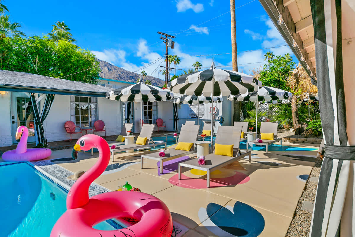 Rectangular pool with pink flamingo floats and white lounge chairs.