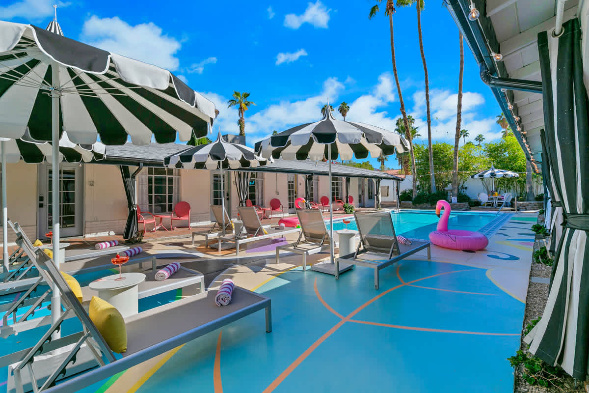 Poolside chairs and umbrellas with colorful deck patterns and rooms beyond.