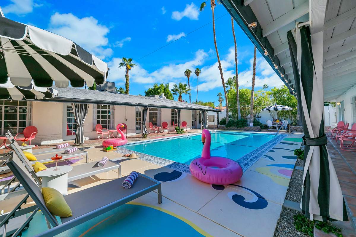 Colorful pool deck with a pink flamingo float, lounge chairs and striped umbrellas.