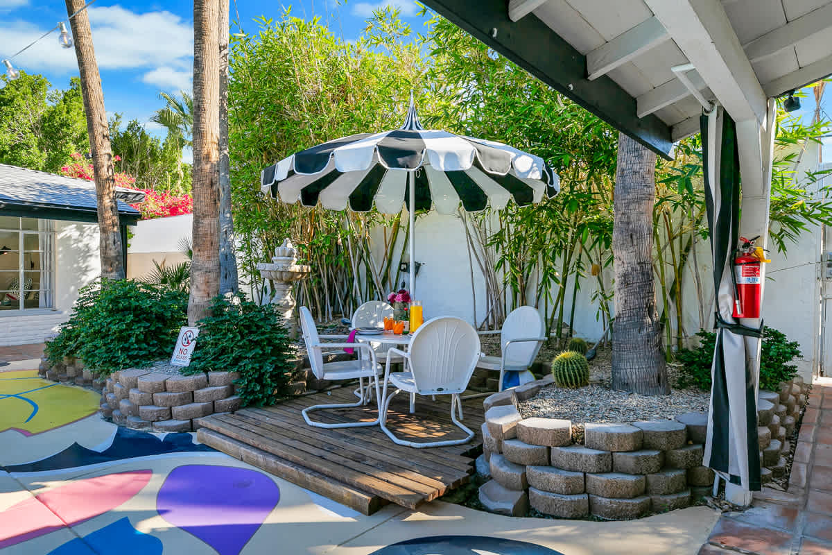 Outdoor seating and striped umbrellas beside a low circular stone wall.