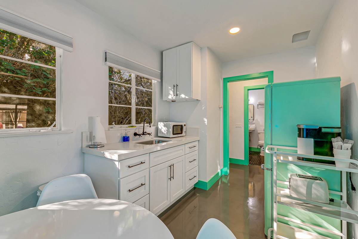 White kitchen cabinets and counter with garden windows and mint-green trim.