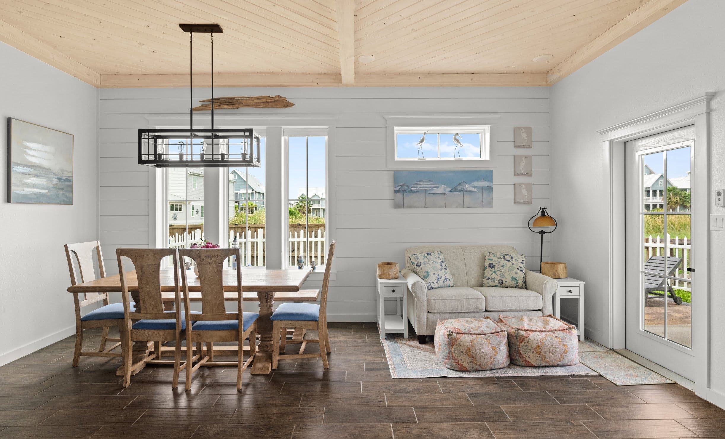 Dining area with trestle table, blue cushion chairs, shiplap walls, and pine ceiling