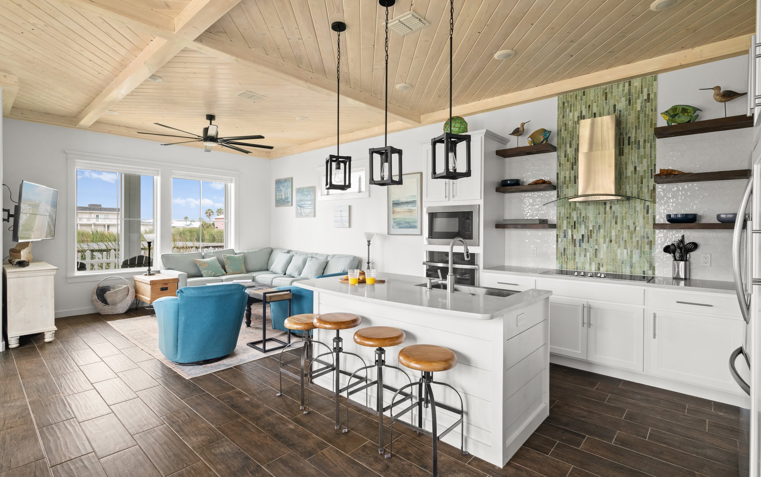Open floor plan with kitchen island, sectional sofa, blue swivel chairs, and pine ceiling