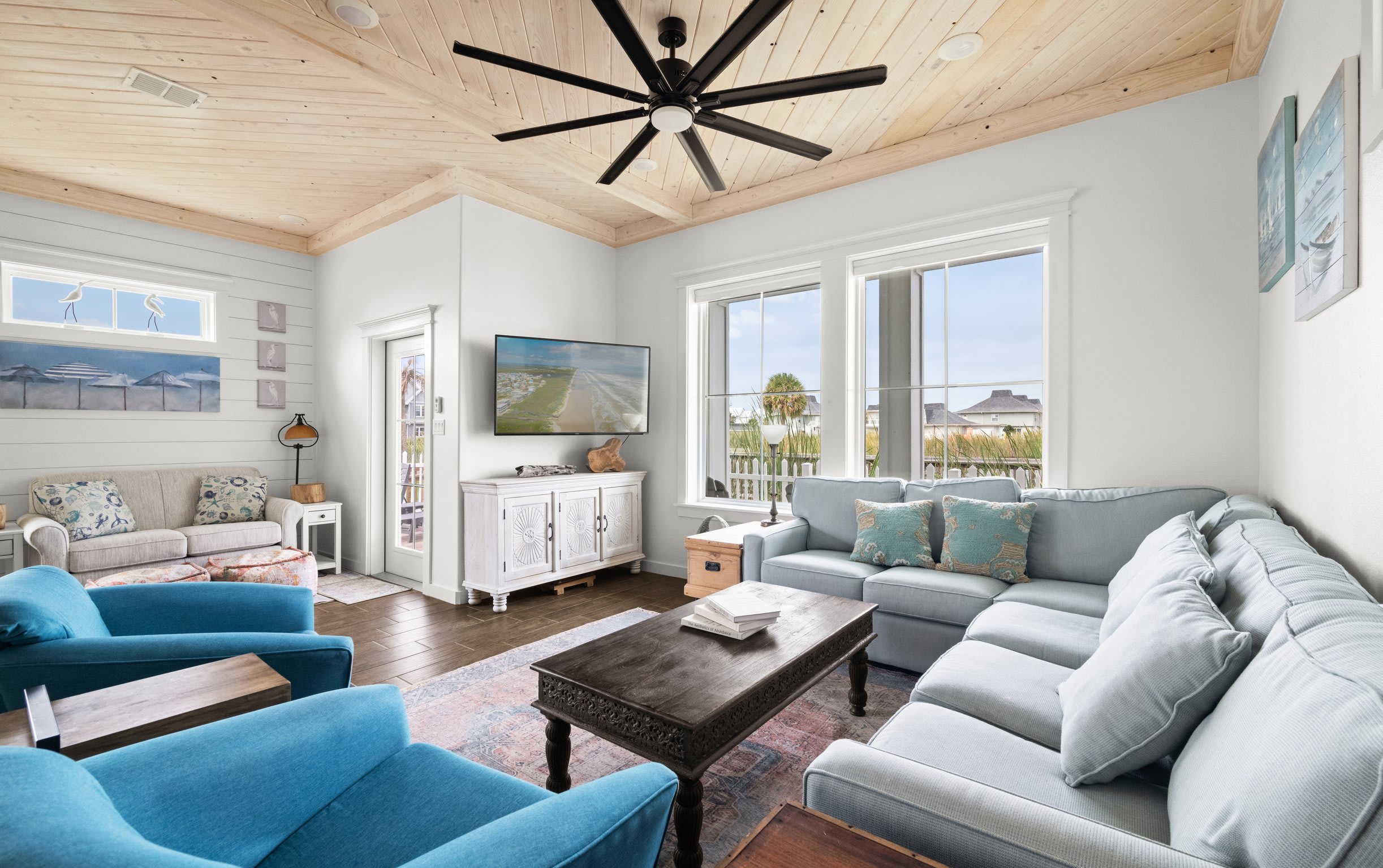 Living room with sectional sofa, blue swivel chairs, wall-mounted TV, and shiplap accent