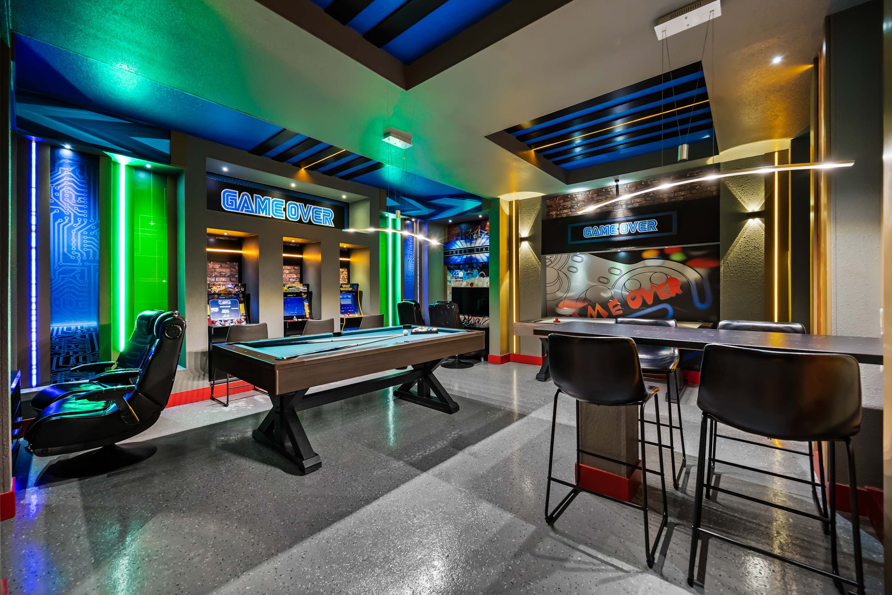 Entertainment lounge with pool table, bar seating, and arcade setup, perfect for game nights.