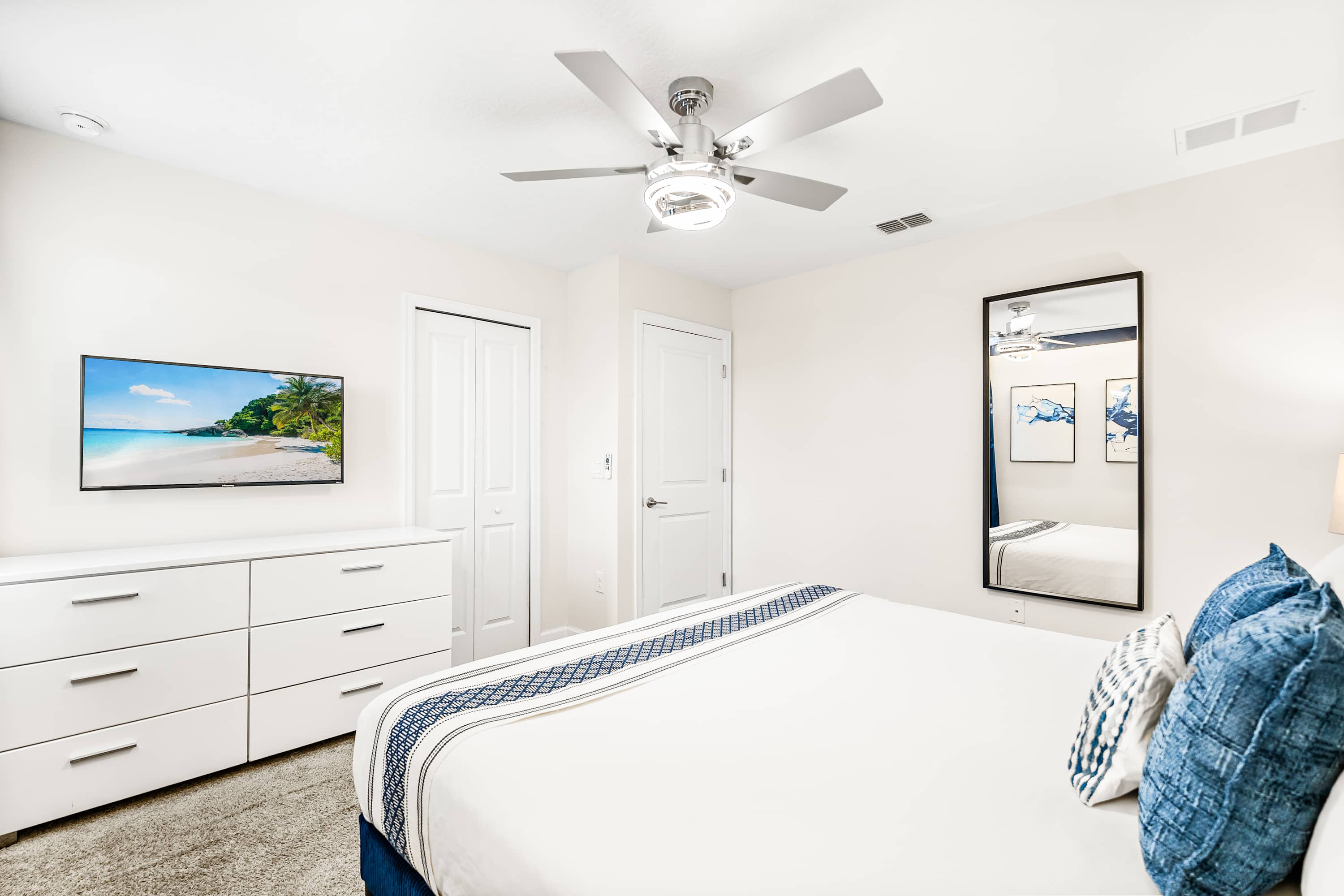 Bright bedroom with spacious layout, ceiling fan, and TV for added comfort.