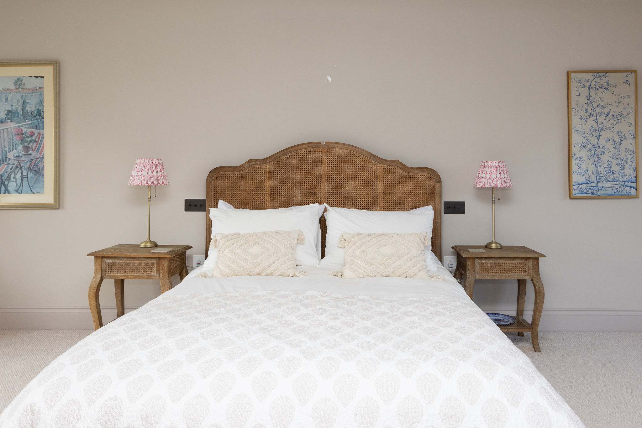 Thoughtfully styled bedroom with a rattan headboard, quality linens, and warm coastal touches.