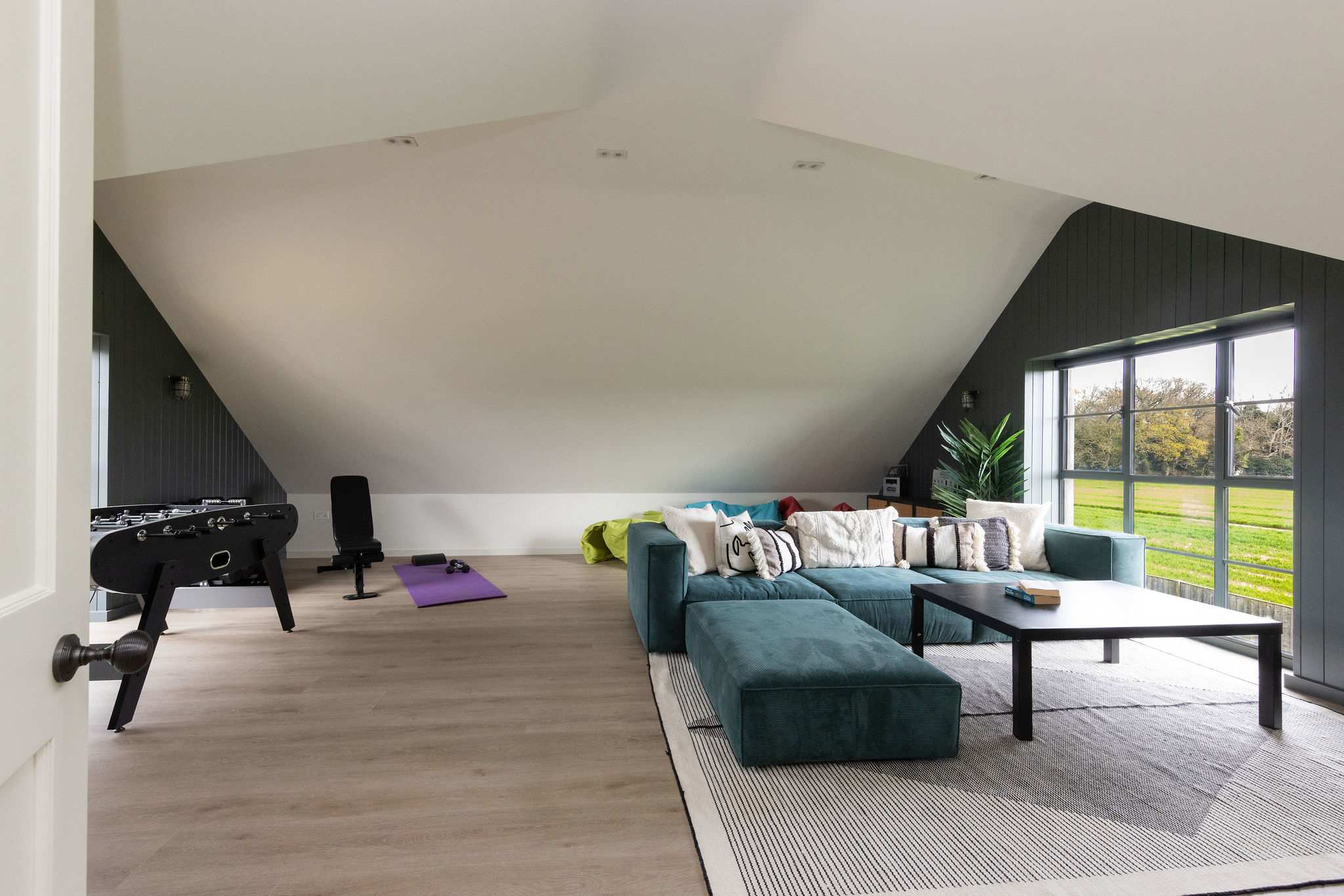 Spacious games room with foosball, comfy seating, and garden views — ideal for unwinding together.