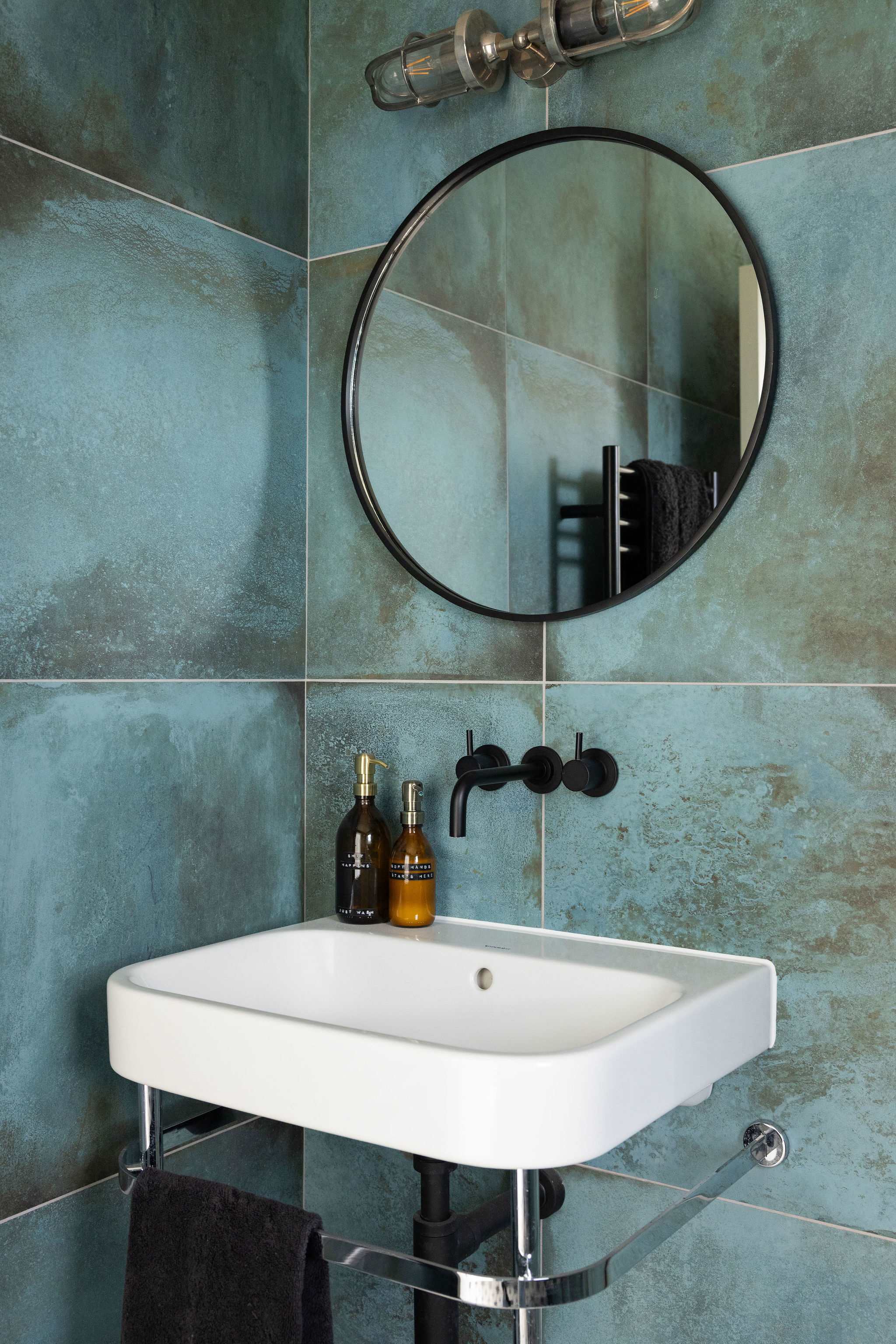 Stylish details at every turn — contemporary basin, matte black fixtures, and textured tiling.