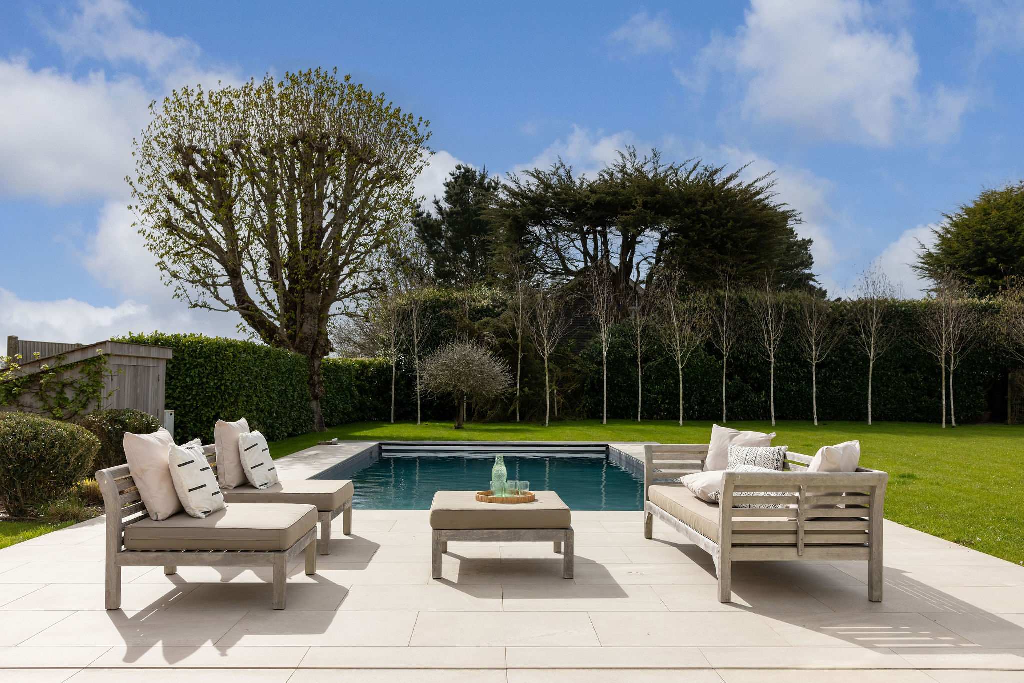 Unwind poolside with comfortable outdoor furniture, countryside views, and endless blue skies above.