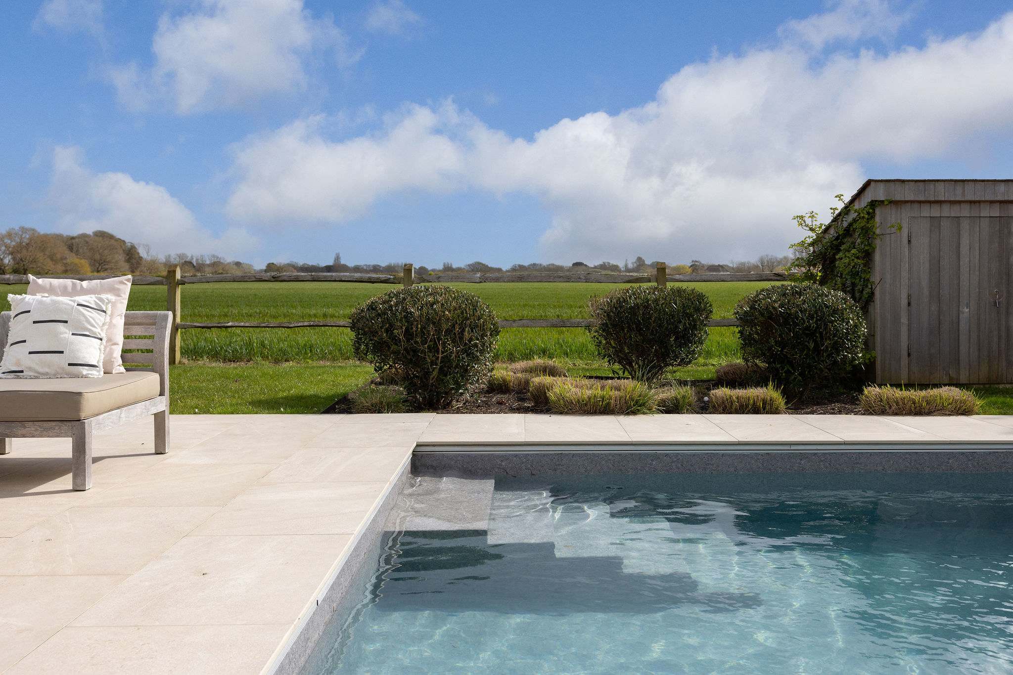 Relax by the heated pool with beautifully manicured hedges and sweeping countryside views beyond.