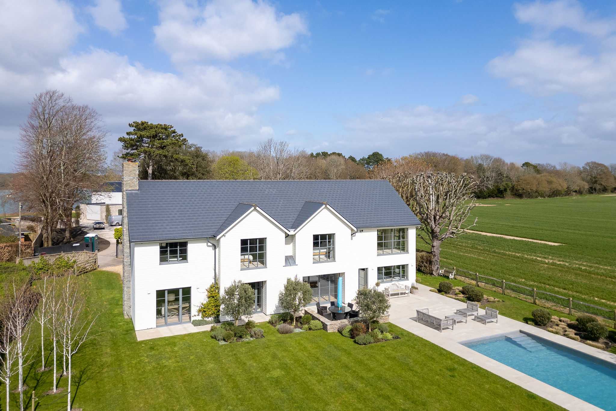 Aerial view showcasing the impressive home, heated pool, and surrounding open countryside setting.