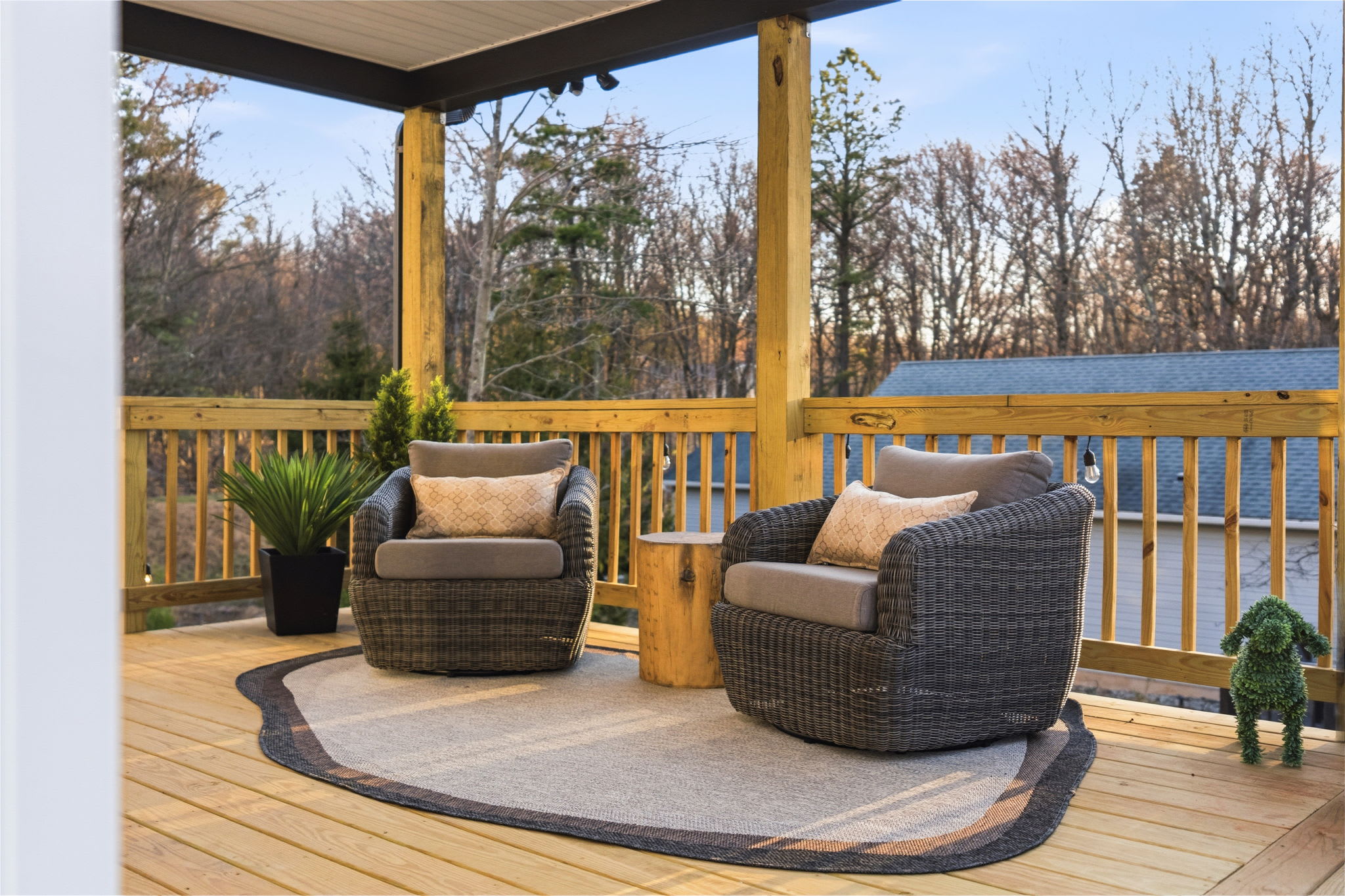 Covered deck wicker lounge with ceiling fan and forest views